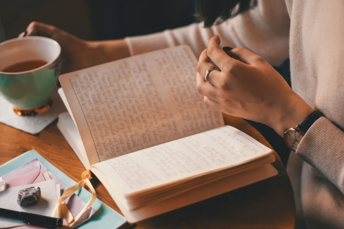 Someone writing in a notebook at a kitchen table