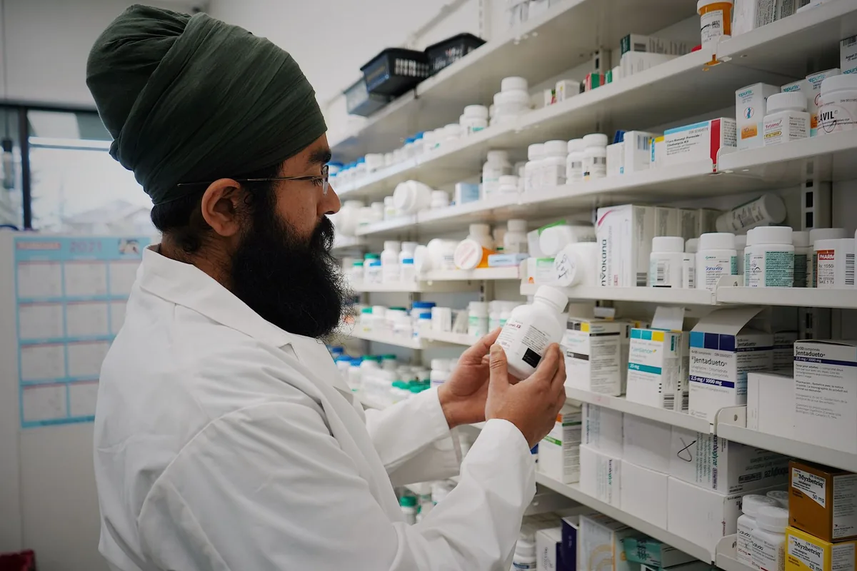 A pharmacist selecting a medicine box from pharmacy shelves