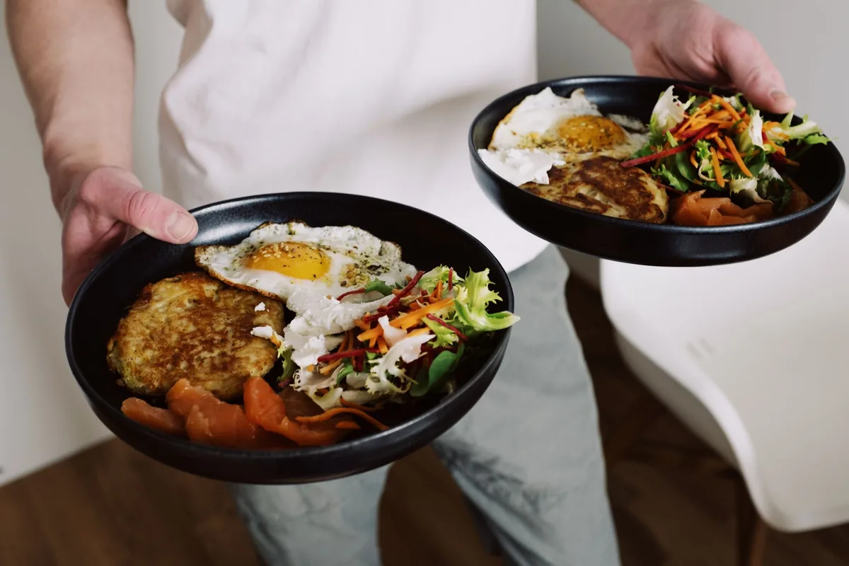 Two bowls of vegetables, rice and egg held at a table